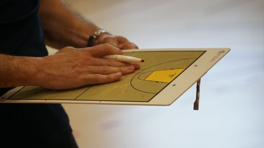 Hands working through plays on a tactics board