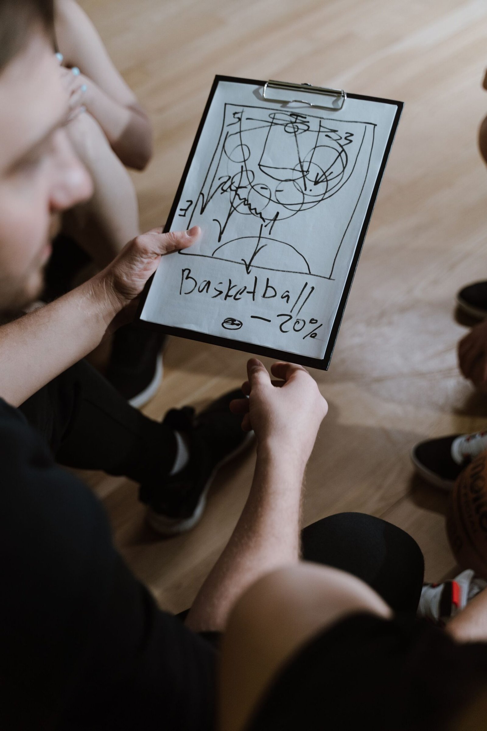 Hands drawing a play on a clipboard