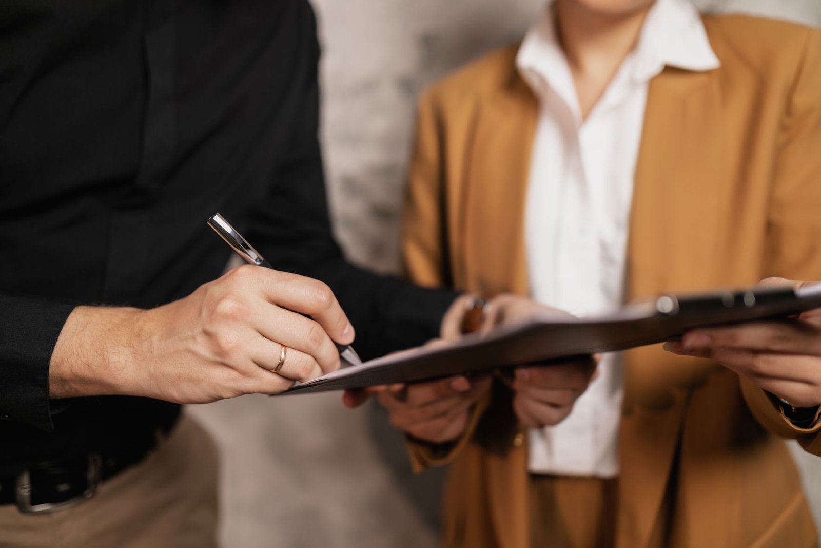 Two professionals signing documents, hands and pen